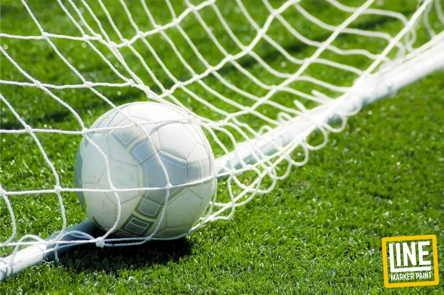 A football at the back of the goal net on cropped artificial turf. How To Mark A Football Pitch
