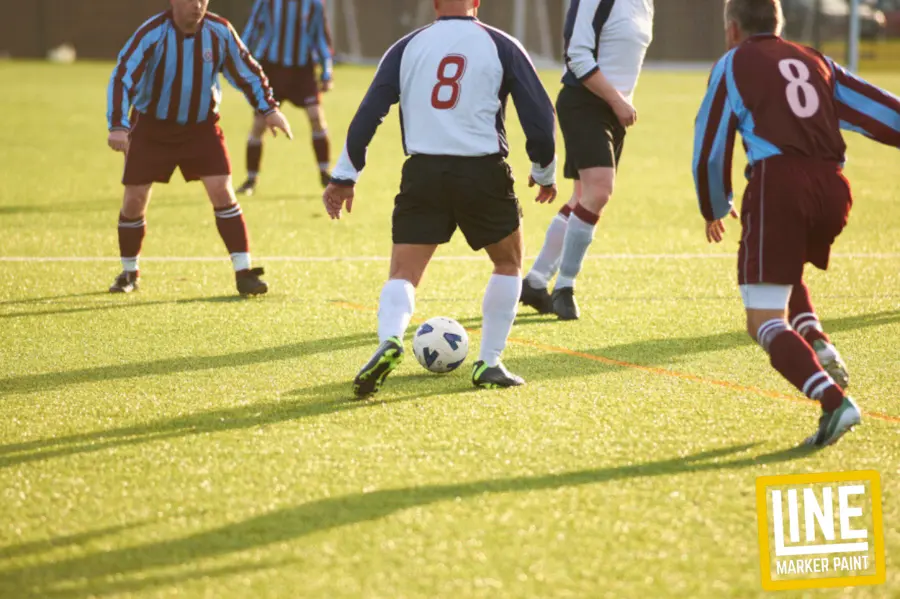 An active game of grassroots football played on a natural grass field. Grassroots Football & Sports